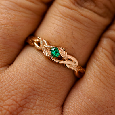 A solid 14k rose gold emerald leaves and vines ring on a model's finger