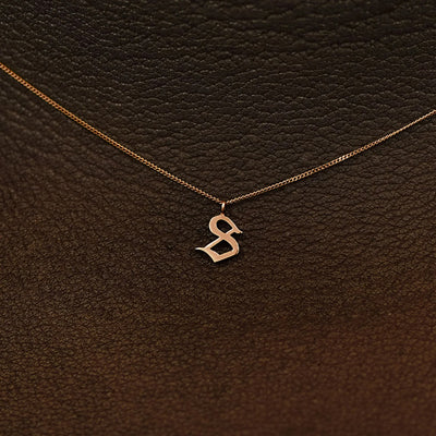 Close up view of a model's neck wearing a 14k solid rose gold Initial Charm Necklace in the letter S