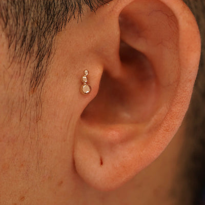 Close up view of a model's ear wearing a 14k rose gold Graduated Ball Flatback as a tragus piercing