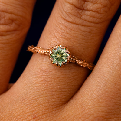 A solid 14k rose gold Green Moissanite Leaf Ring on a model's finger