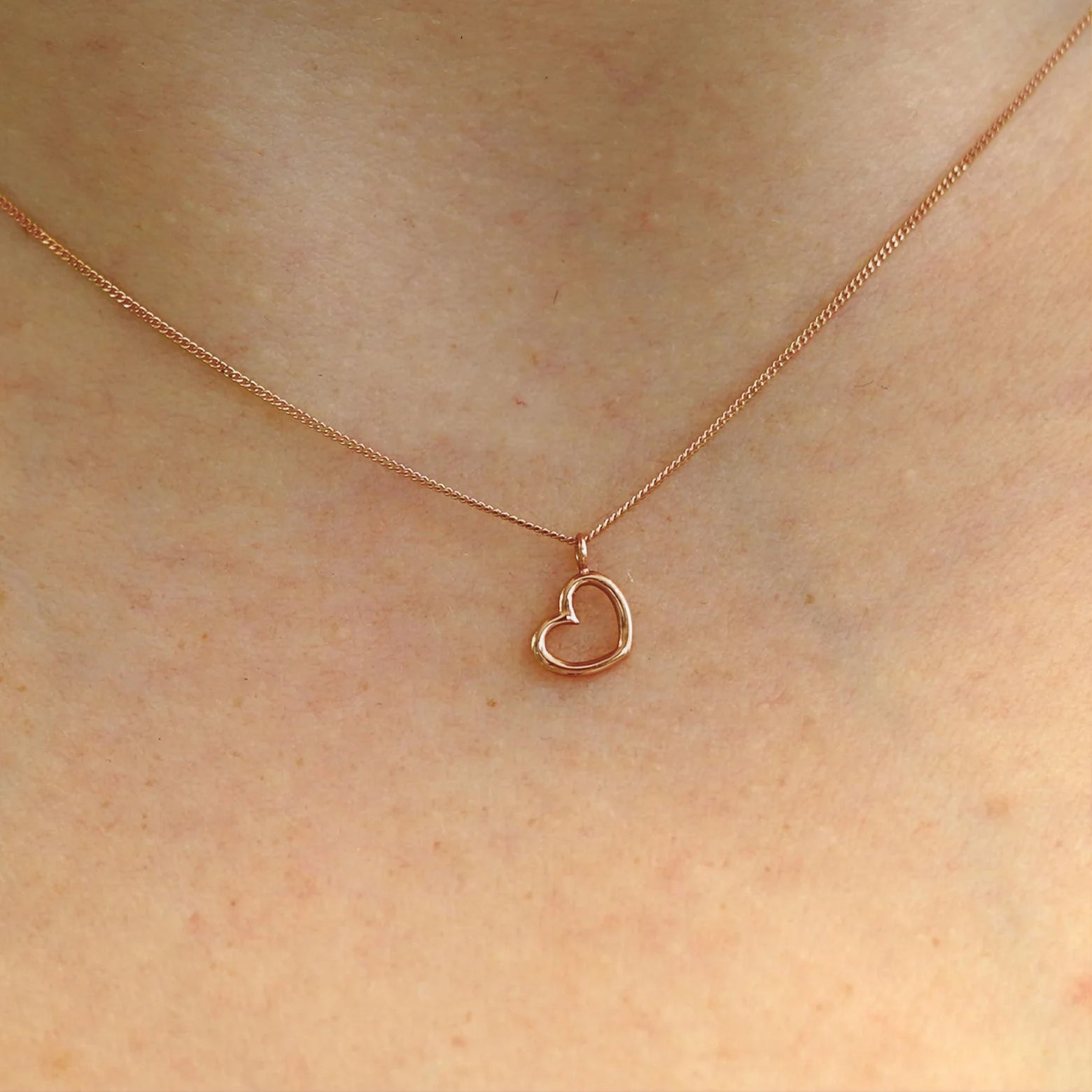 Close up view of a model's neck wearing a 14k rose gold Heart Necklace