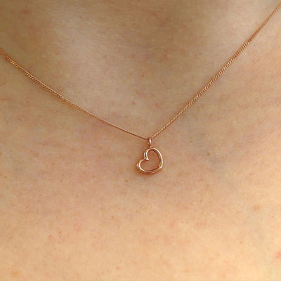 Close up view of a model's neck wearing a 14k rose gold Heart Necklace