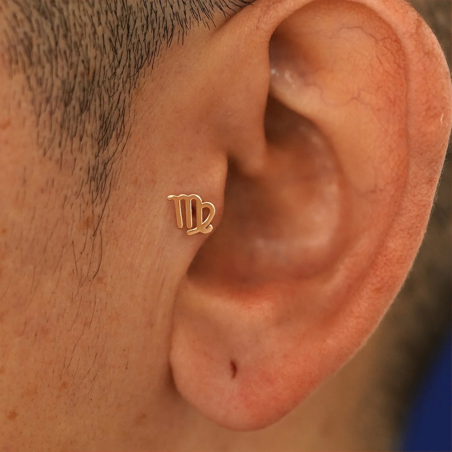 A model's ear wearing a 14k rose gold Virgo Horoscope Flatback in a tragus piercing