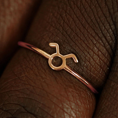 Close up view of a model's fingers wearing a 14k rose gold Taurus Horoscope Ring