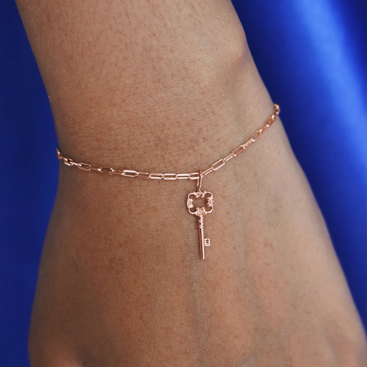 Close up view of a model's wrist wearing a rose gold Key Charm on a Butch Bracelet