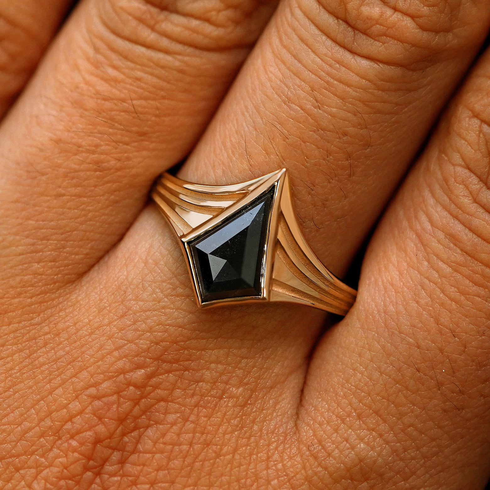 Close up view of a model's fingers wearing a 14k rose gold kite black diamond engraved journey ring