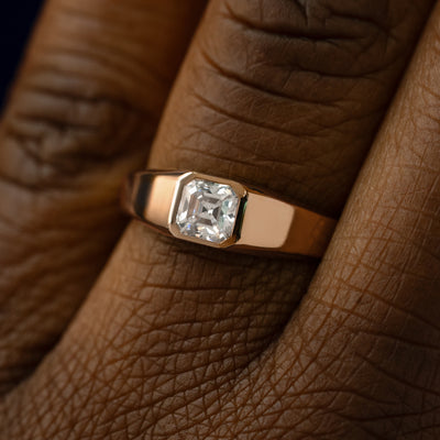 Close up view of a models hand wearing a 14k rose gold asscher lab gemstone ring