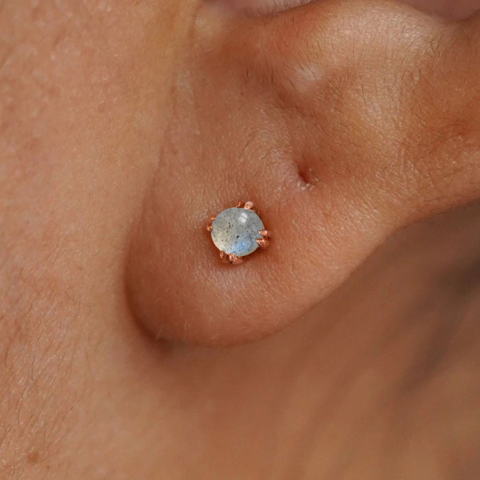 Close up view of a model's ear wearing a rose gold labradorite earring
