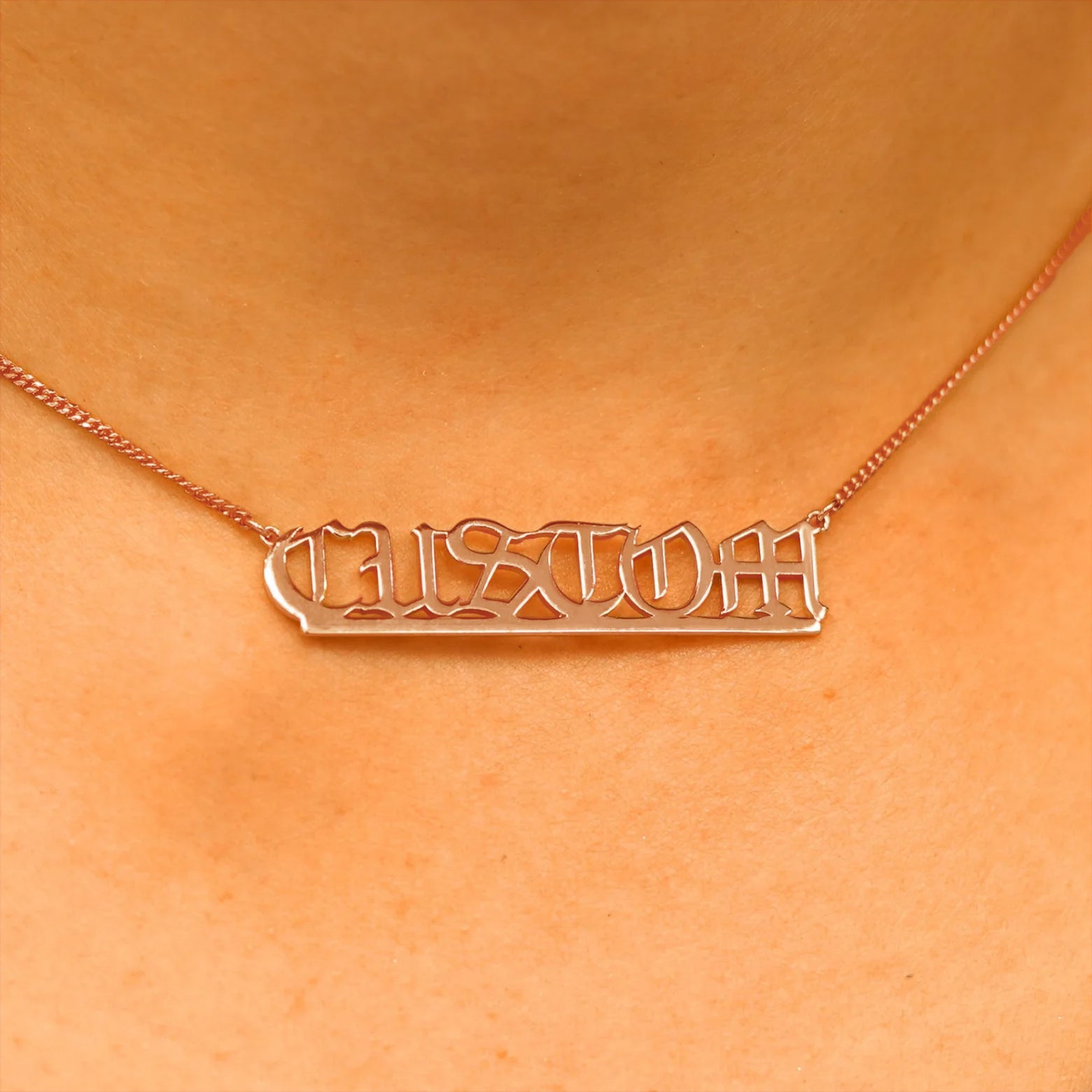 Close up view of a model's neck wearing a Large Custom Nameplate necklace that reads the word Custom