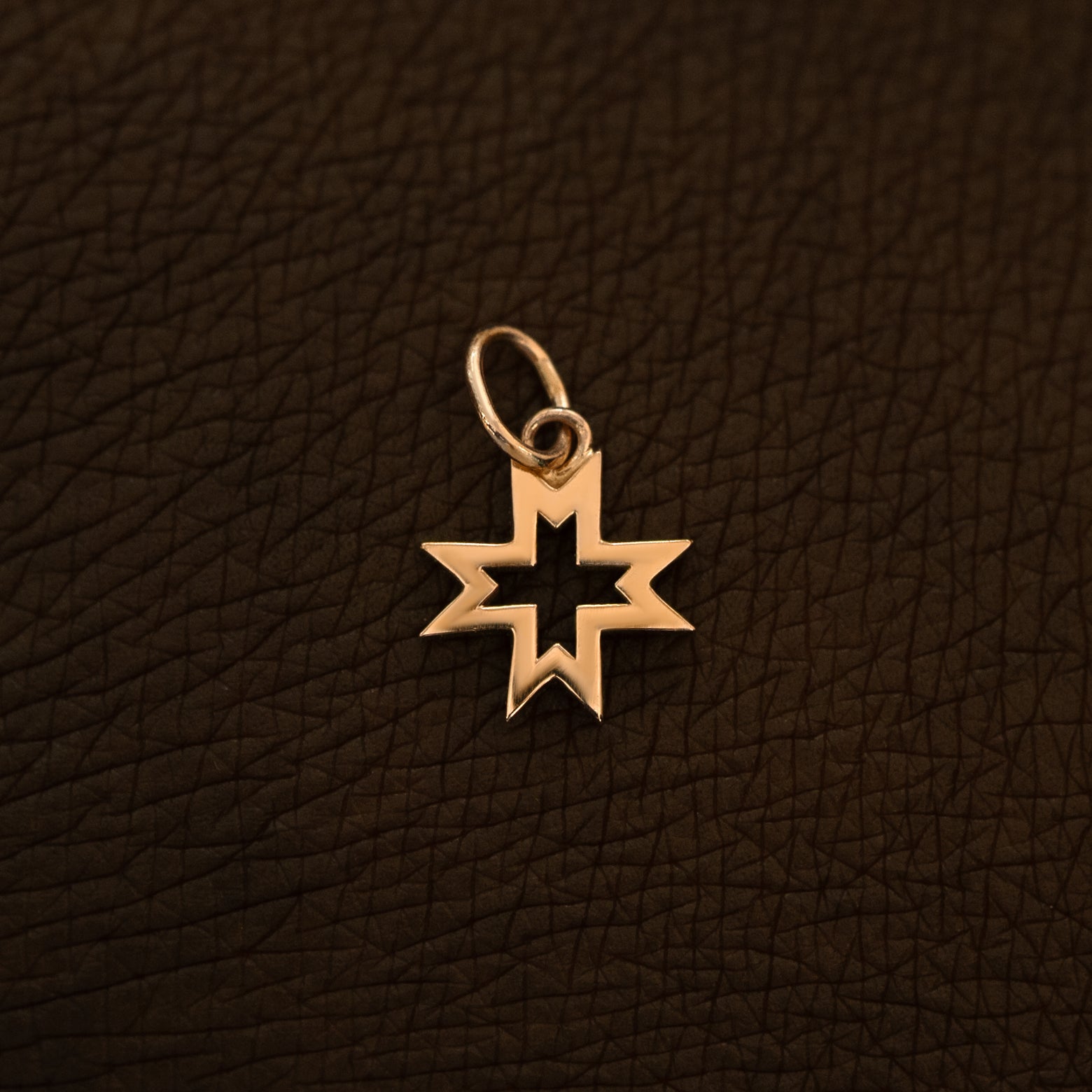 A 14 karat rose solid gold Large Open 8 Pointed Star Charm on the back of a model's hand