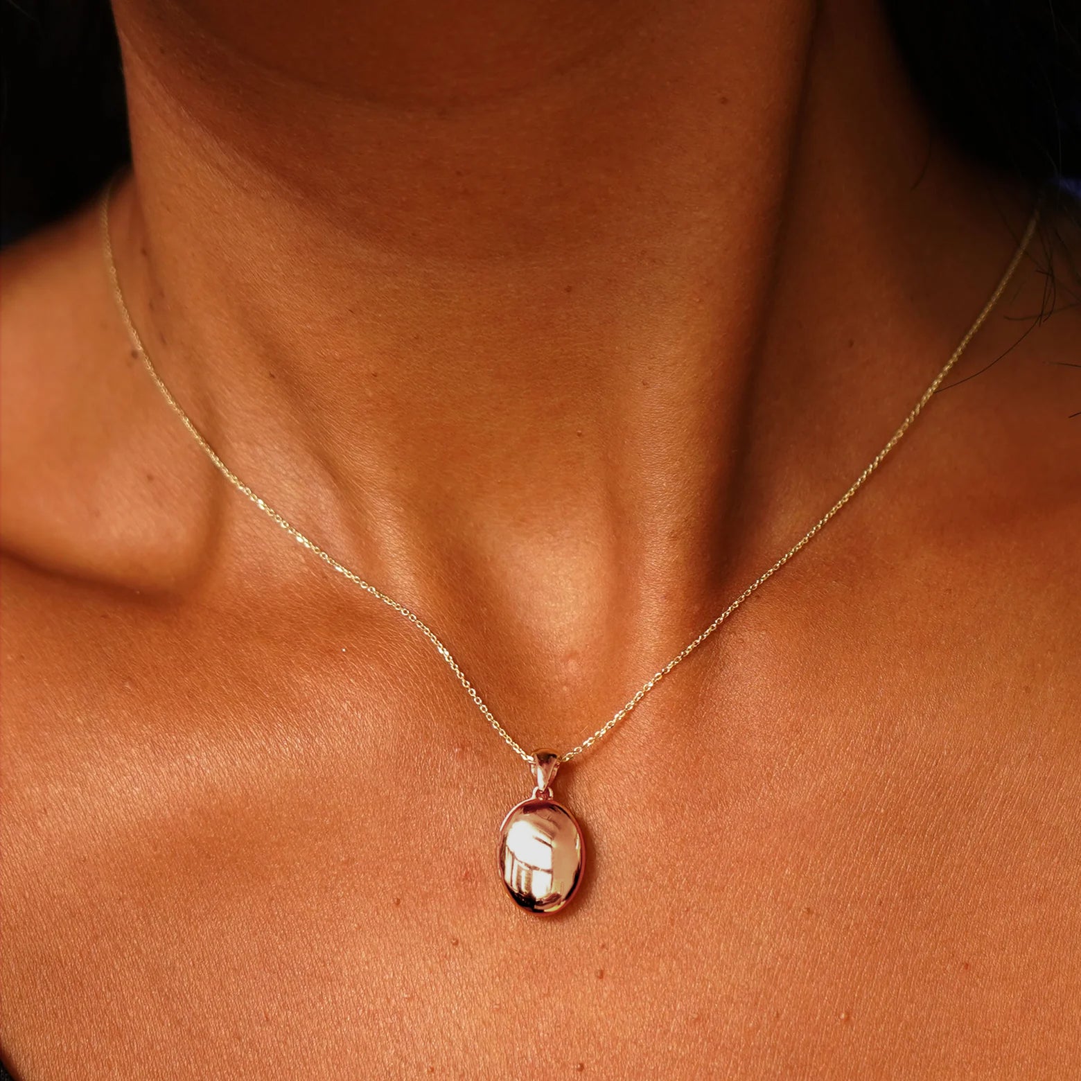 Close up view of a model's neck wearing a rose gold Oval Locket Pendant on a Cable Chain
