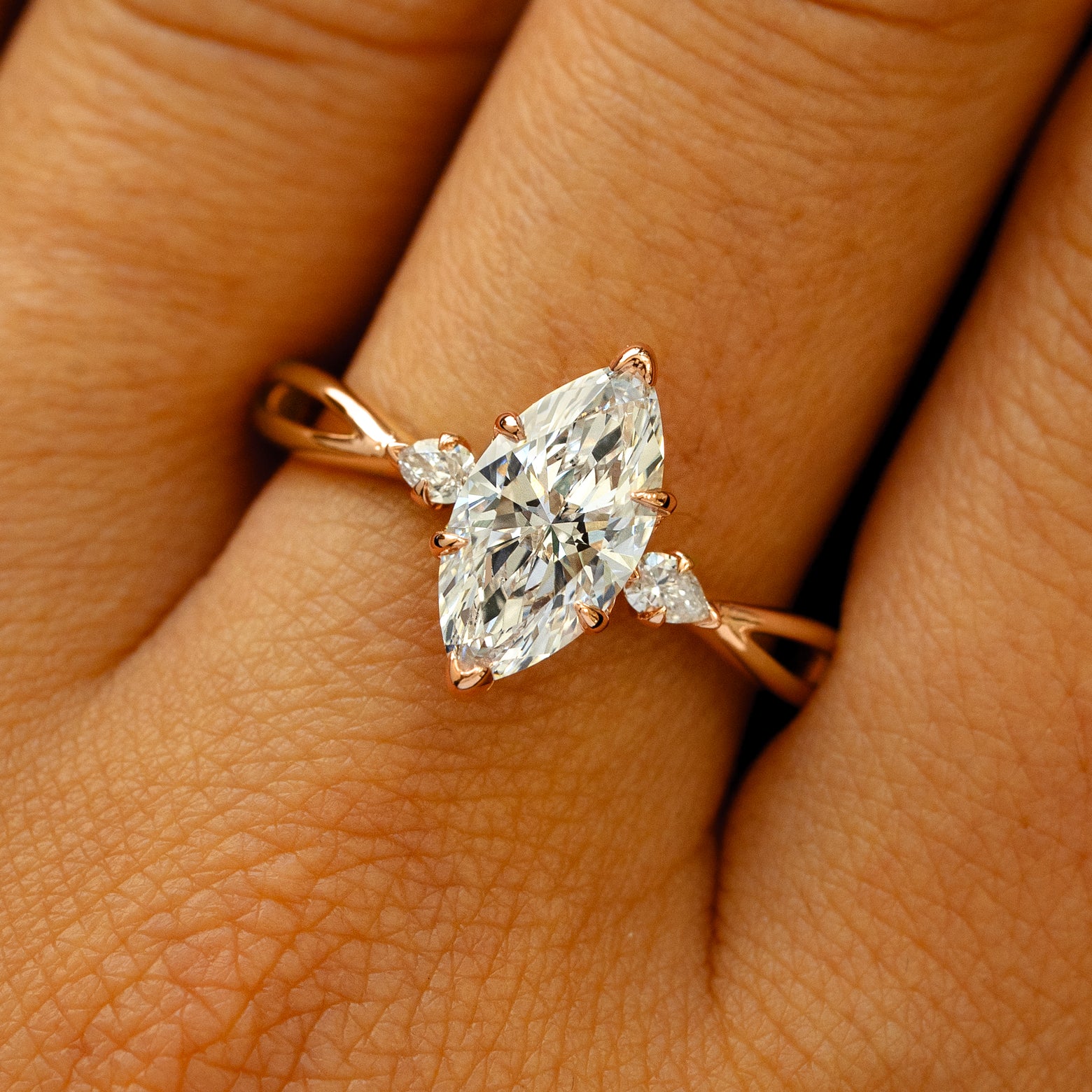A solid 14k rose gold Marquise Lab Diamond Three Stone Ring on a model's finger