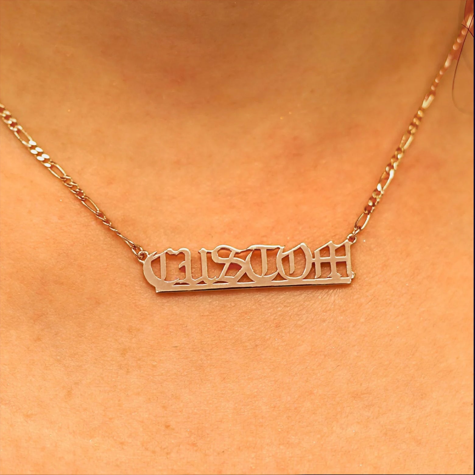 Close up view of a model's neck wearing a Medium Custom Nameplate necklace that reads the word Custom