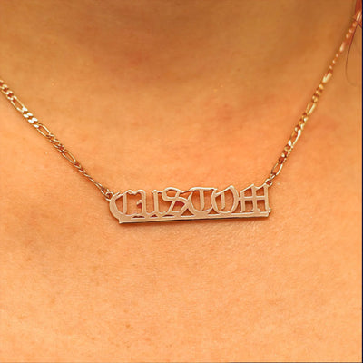 Close up view of a model's neck wearing a Medium Custom Nameplate necklace that reads the word Custom