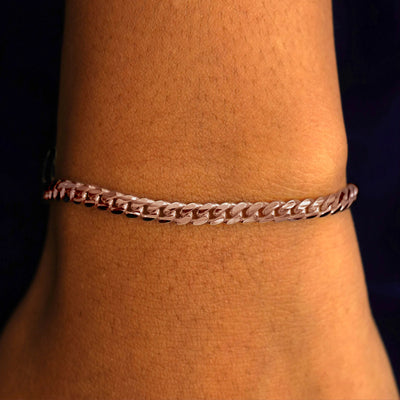 A model's wrist wearing a 14k solid rose gold Medium Miami Bracelet