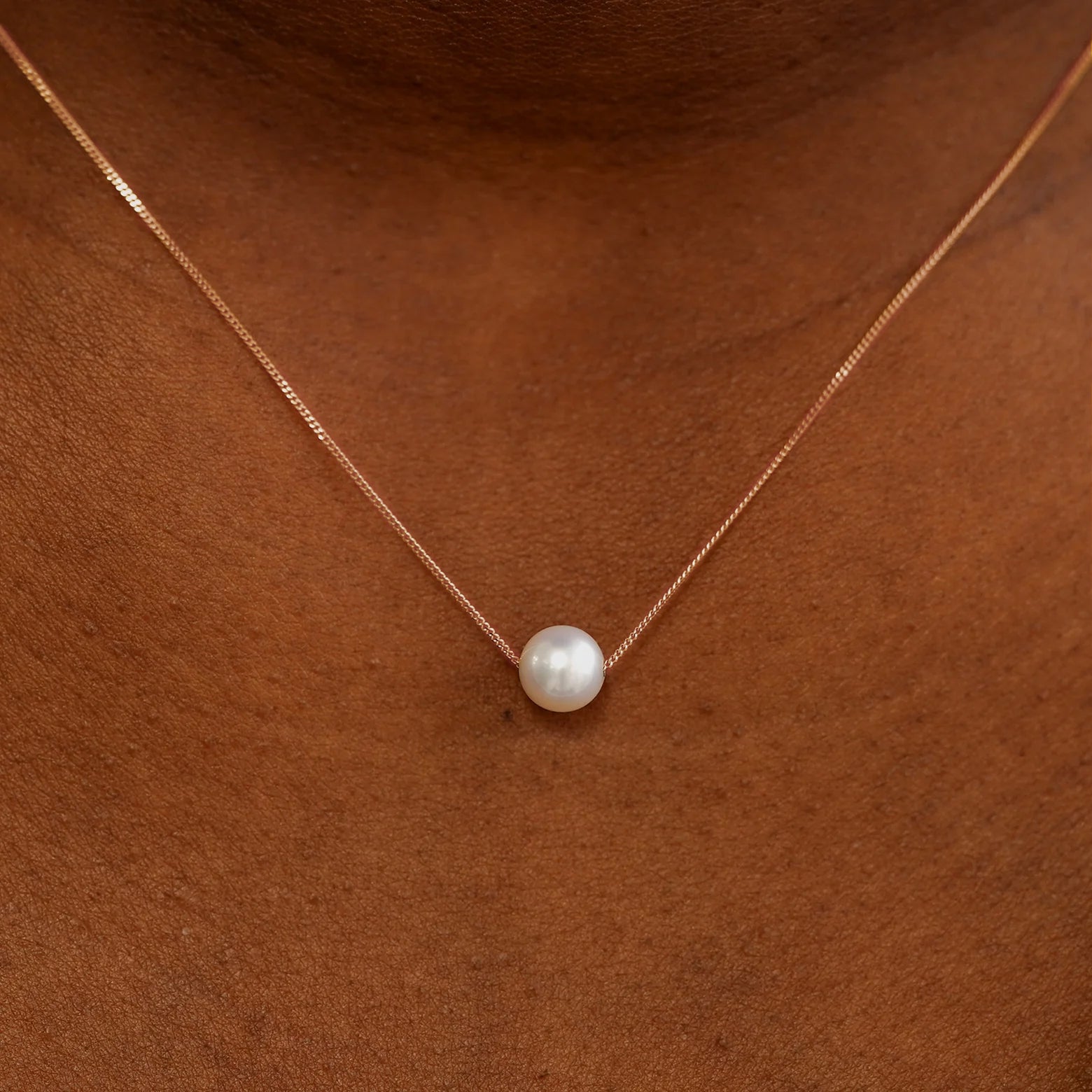 Close up view of a model's neck wearing a rose gold Pearl Slide Necklace with a 6mm pearl