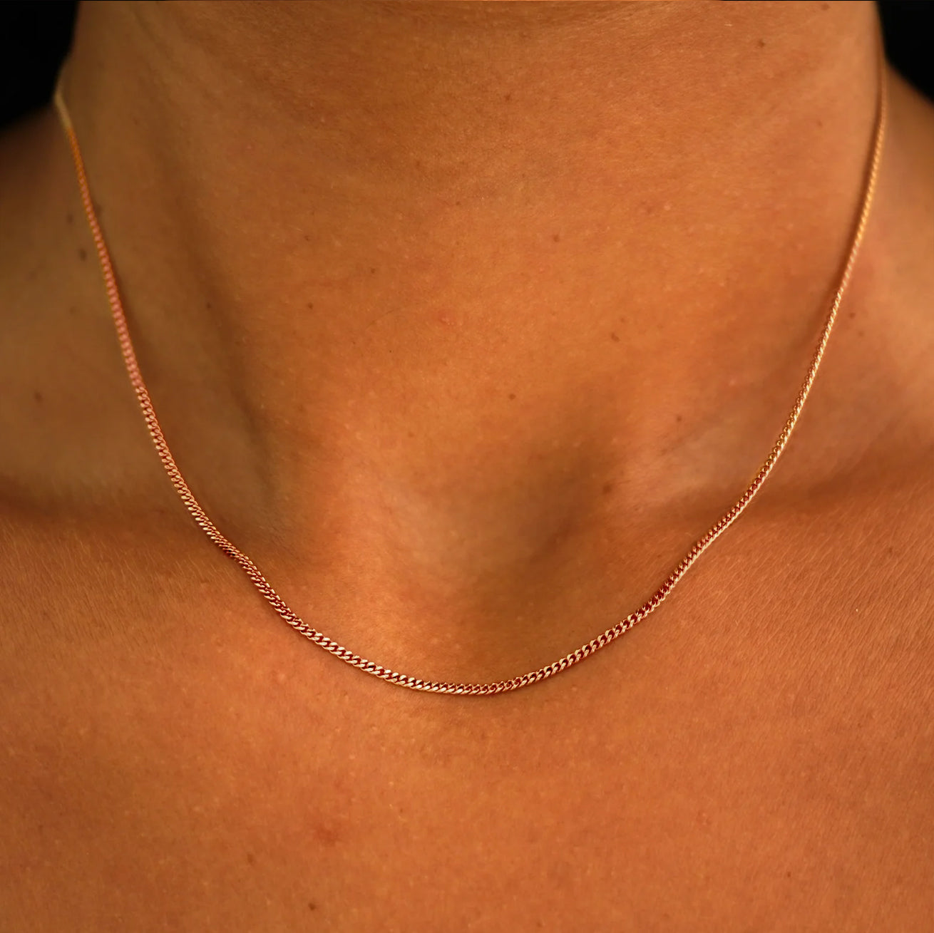 Close up view of a model's neck wearing a solid rose gold Mini Miami Chain