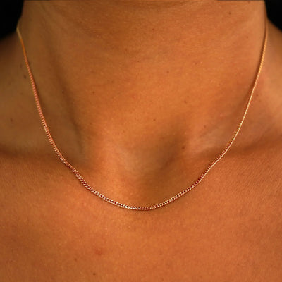 Close up view of a model's neck wearing a solid rose gold Mini Miami Chain