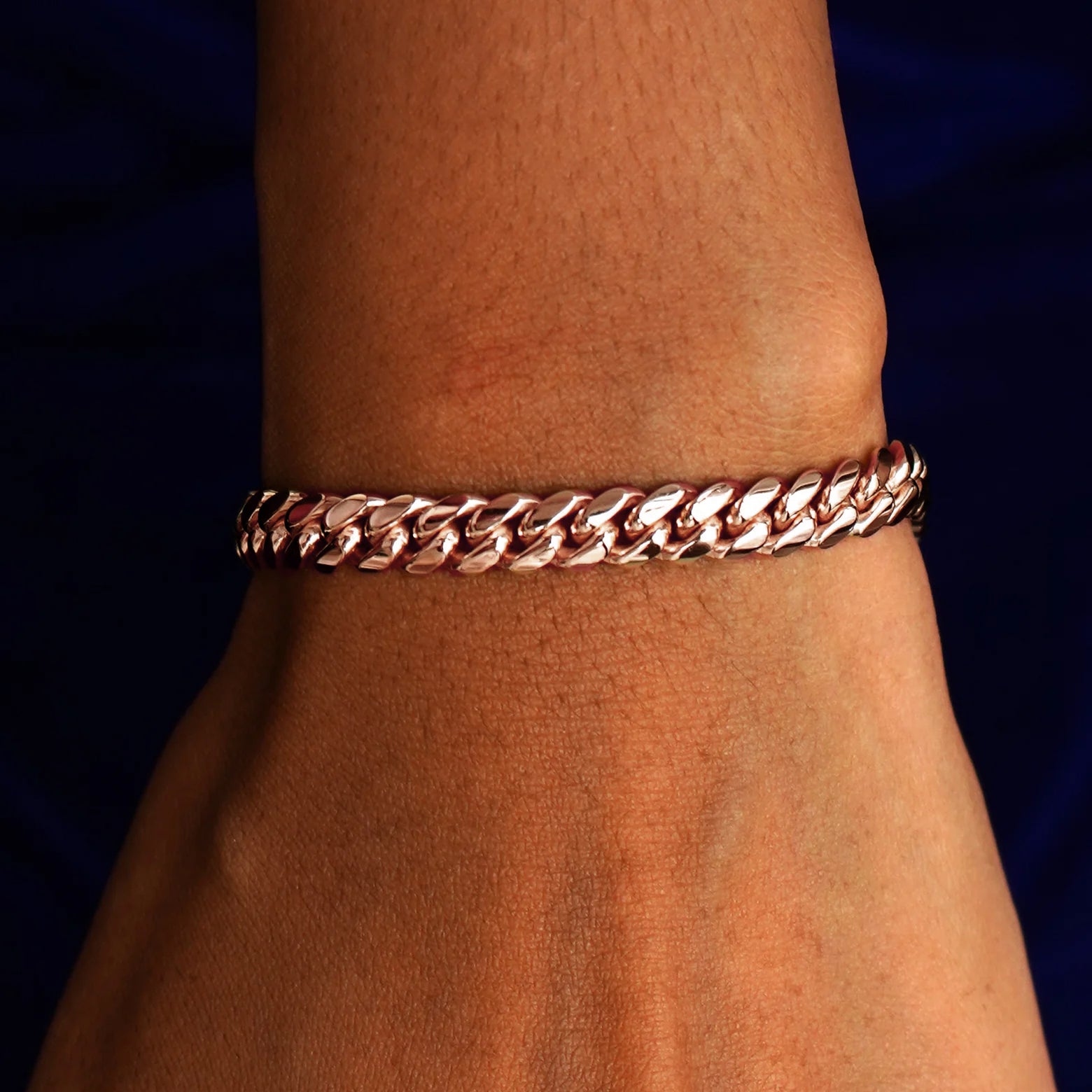 A model's wrist wearing a solid 14k rose gold Miami Cuban Bracelet