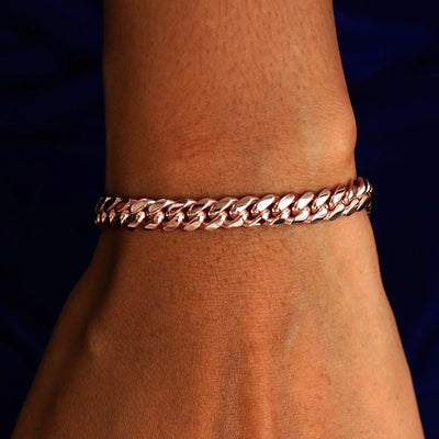 A model's wrist wearing a solid 14k rose gold Miami Cuban Bracelet