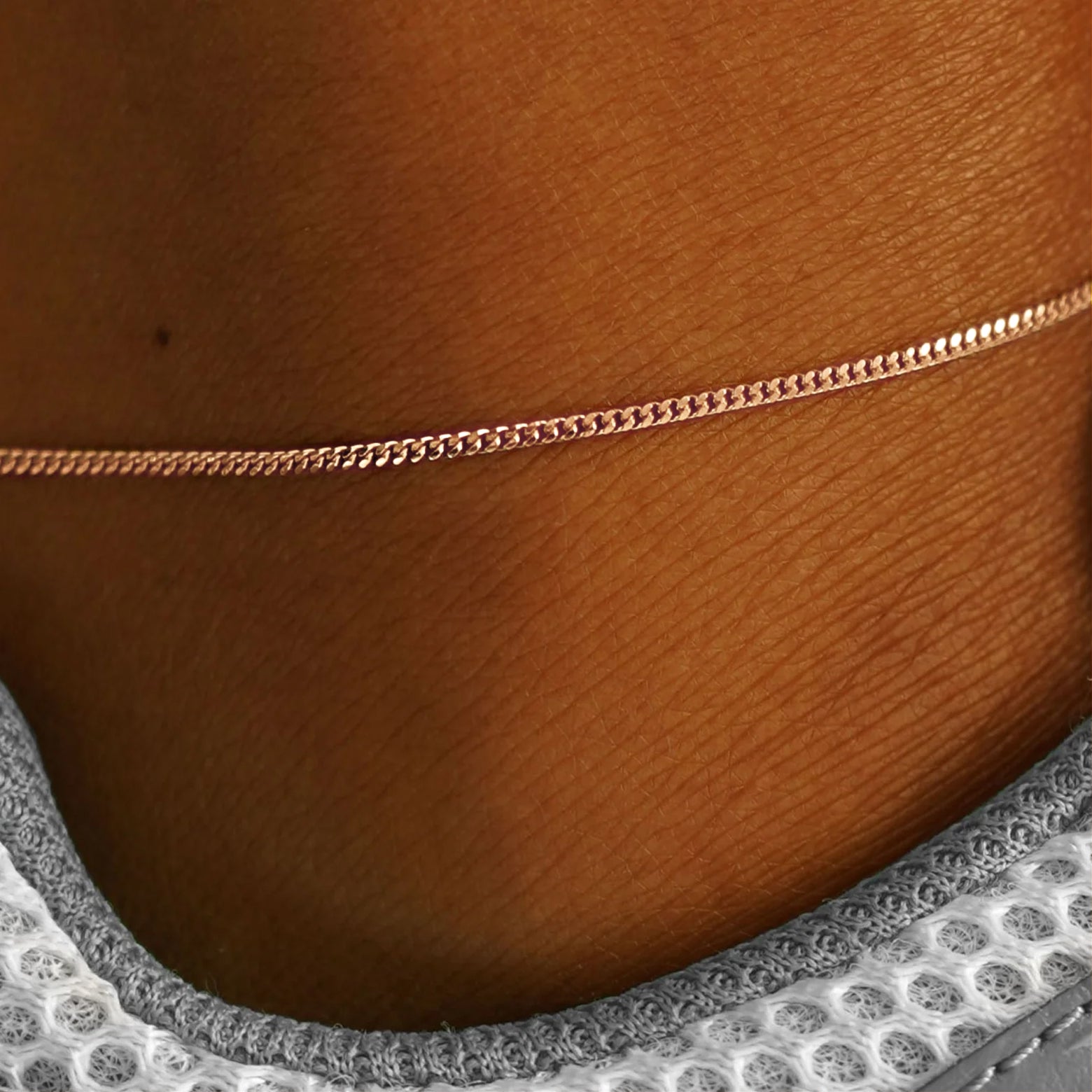 Close up view of a model's ankle wearing a solid rose gold Mini Miami Anklet