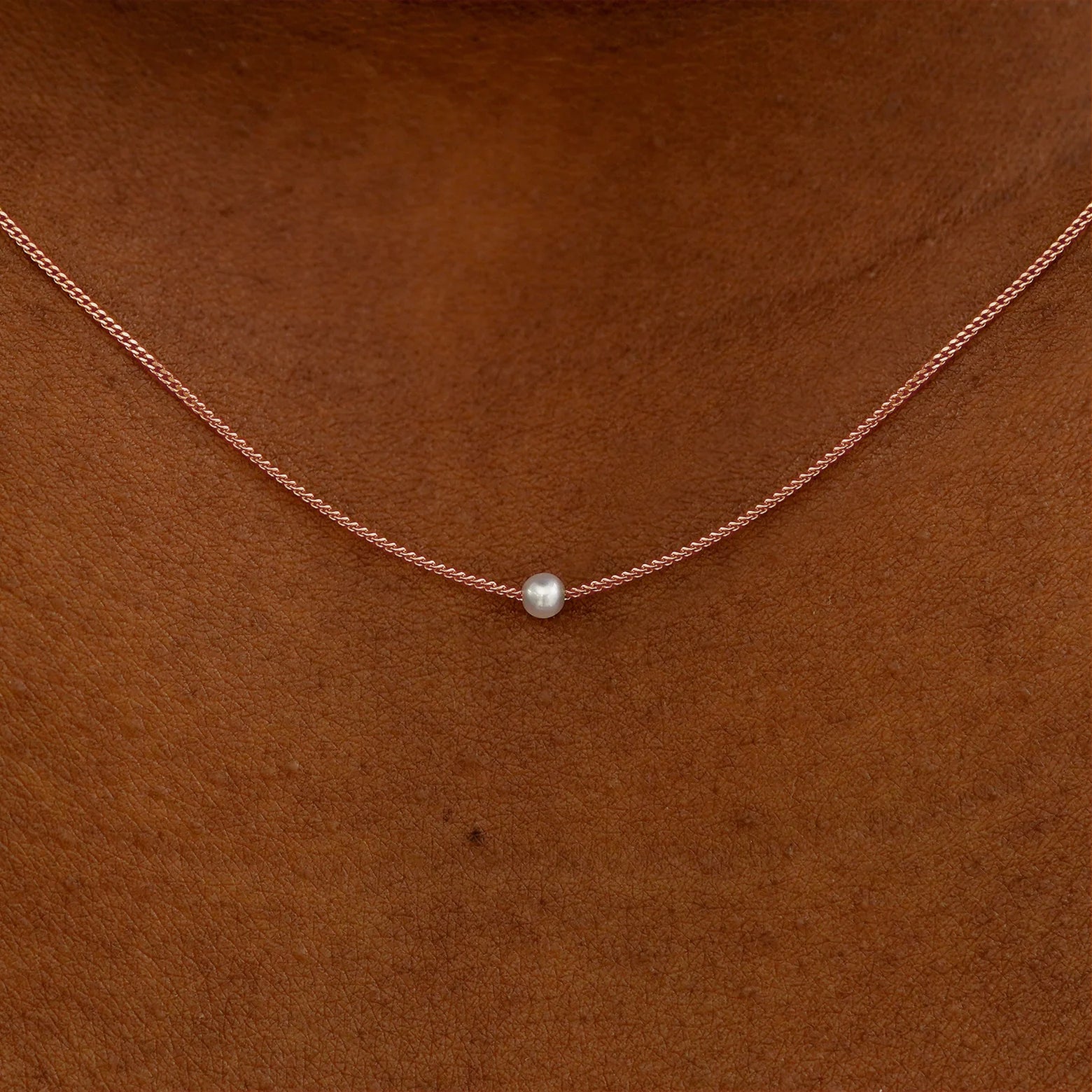 Close up view of a model's neck wearing a rose gold Pearl Slide Necklace with a 2mm pearl