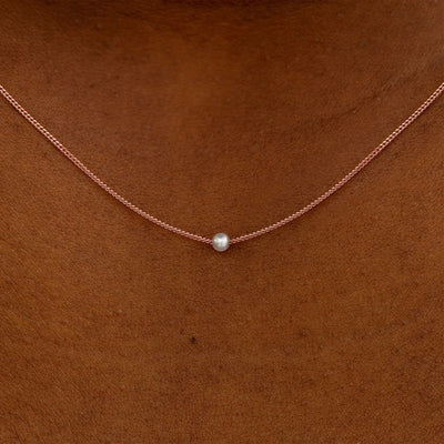 Close up view of a model's neck wearing a rose gold Pearl Slide Necklace with a 2mm pearl