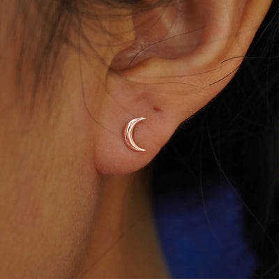 Close up view of a model's ear wearing a rose gold Moon Flat Back Earring