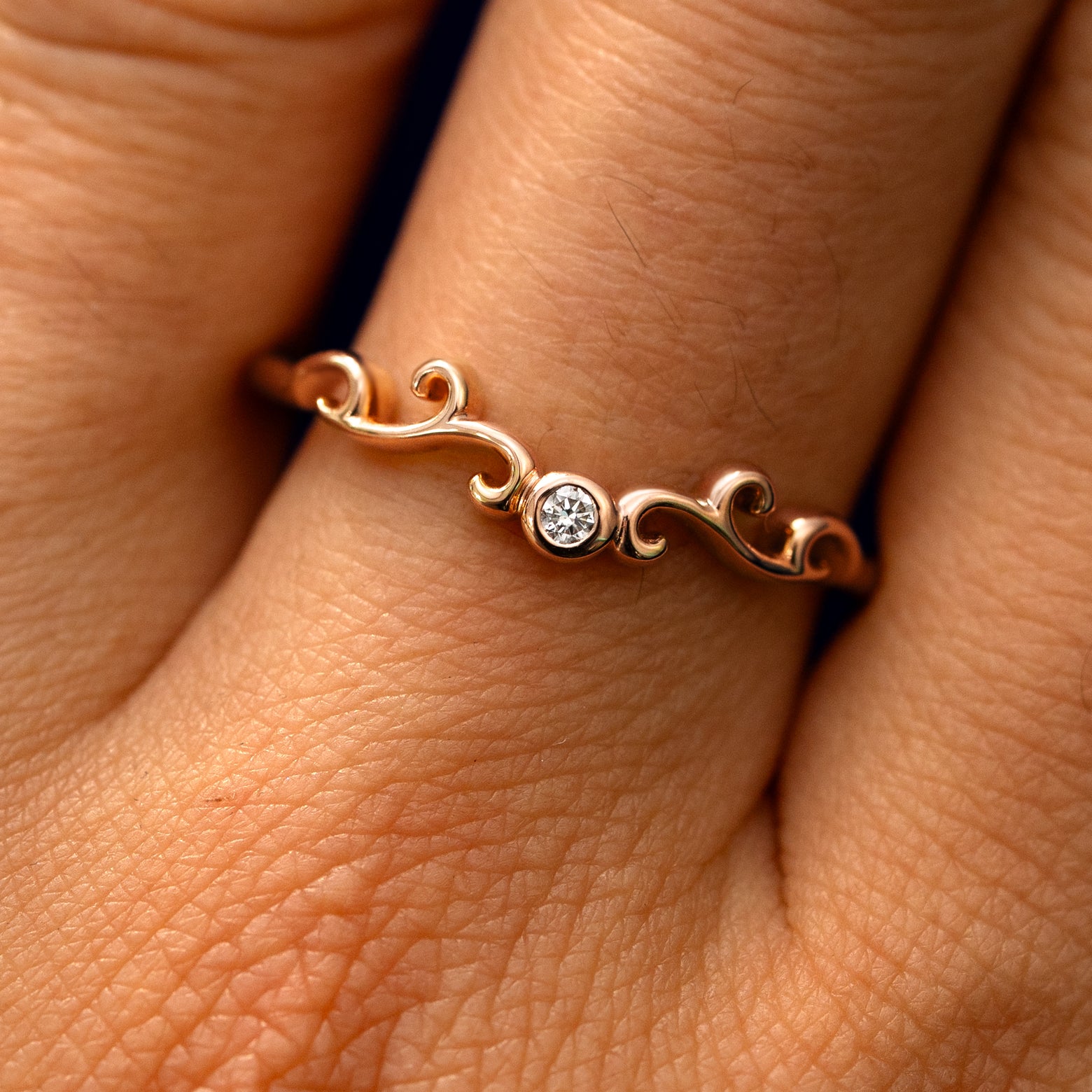 Close up view of a model's fingers wearing a 14k rose gold Open Filigree Chevron Diamond Band
