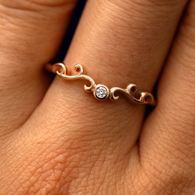 Close up view of a model's fingers wearing a 14k rose gold Open Filigree Chevron Diamond Band
