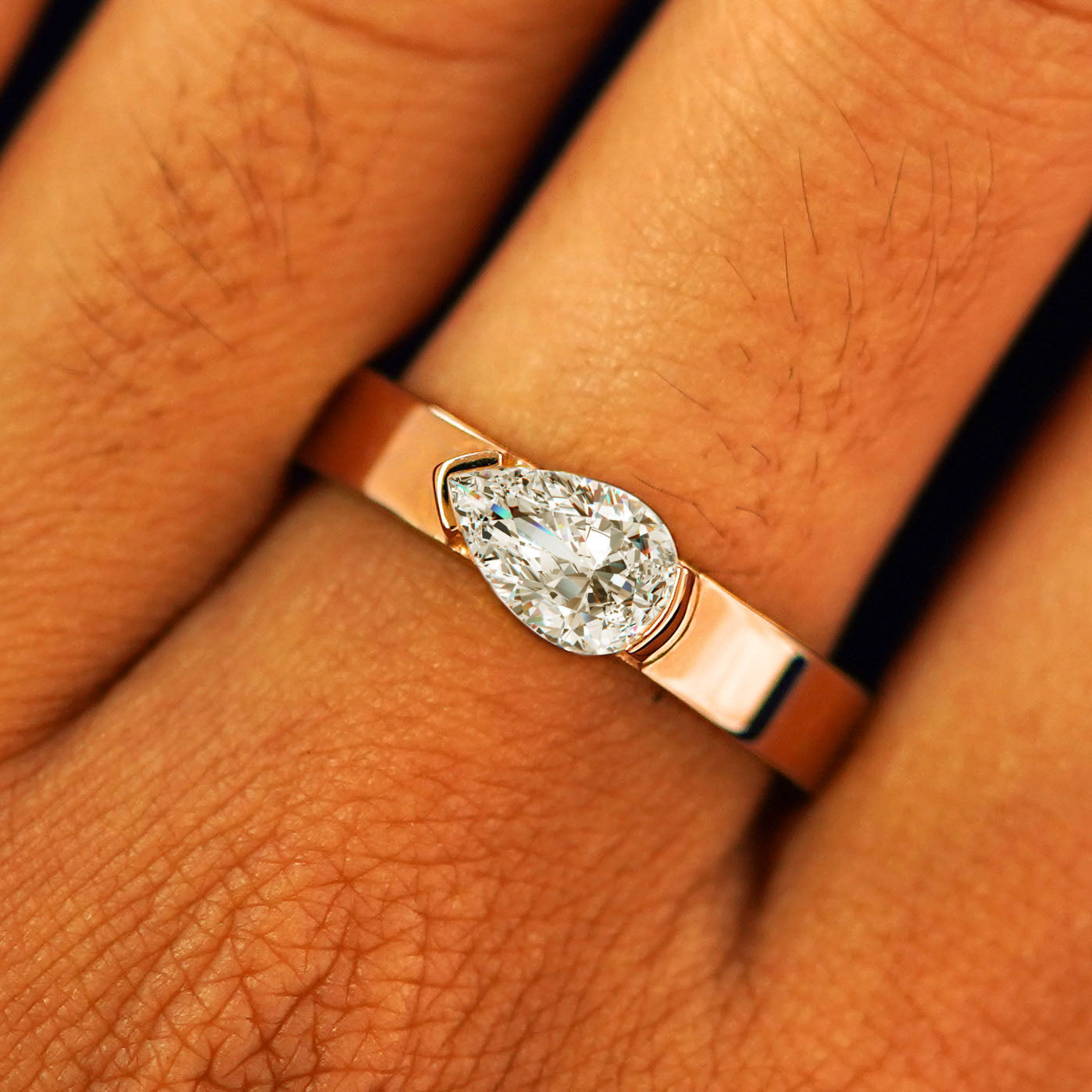Close up view of a model's fingers wearing a 14k rose gold Lab Diamond Pear Ring