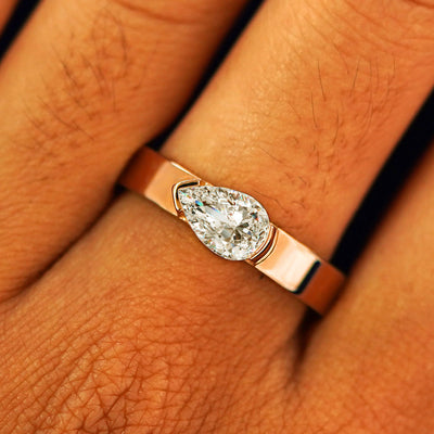 Close up view of a model's fingers wearing a 14k rose gold Lab Diamond Pear Ring
