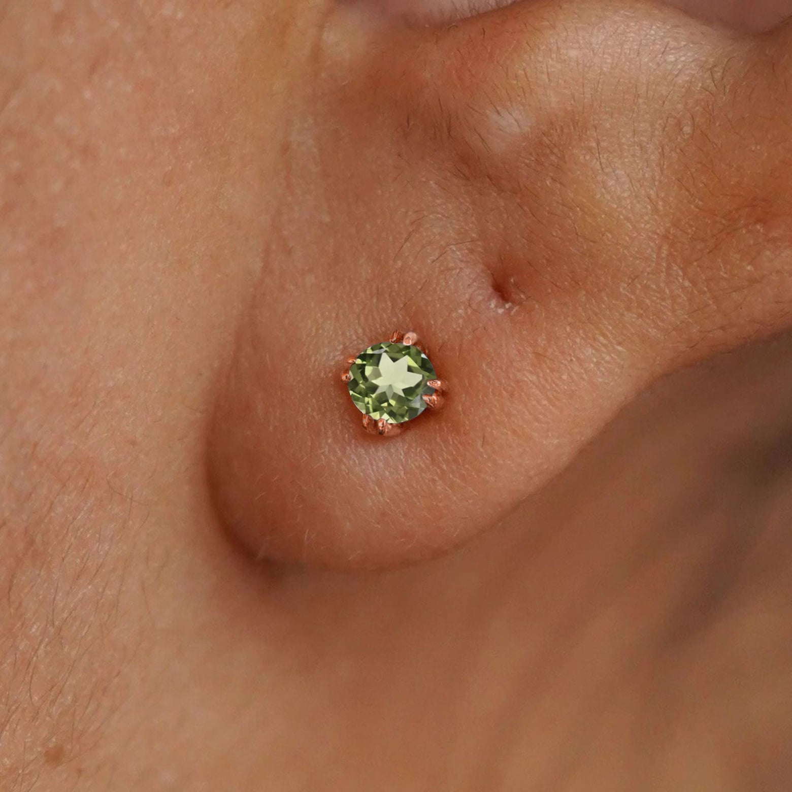 Close up view of a model's ear wearing a 14k rose gold Peridot Earring