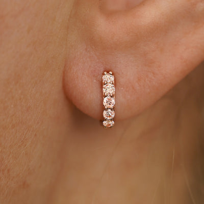 Close up view of a model's ear wearing a rose gold Small Pink Lab Diamond Huggie Hoop