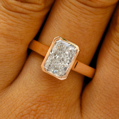A solid 14k rose gold Radiant Cut Lab Diamond Cathedral Ring on a model's finger