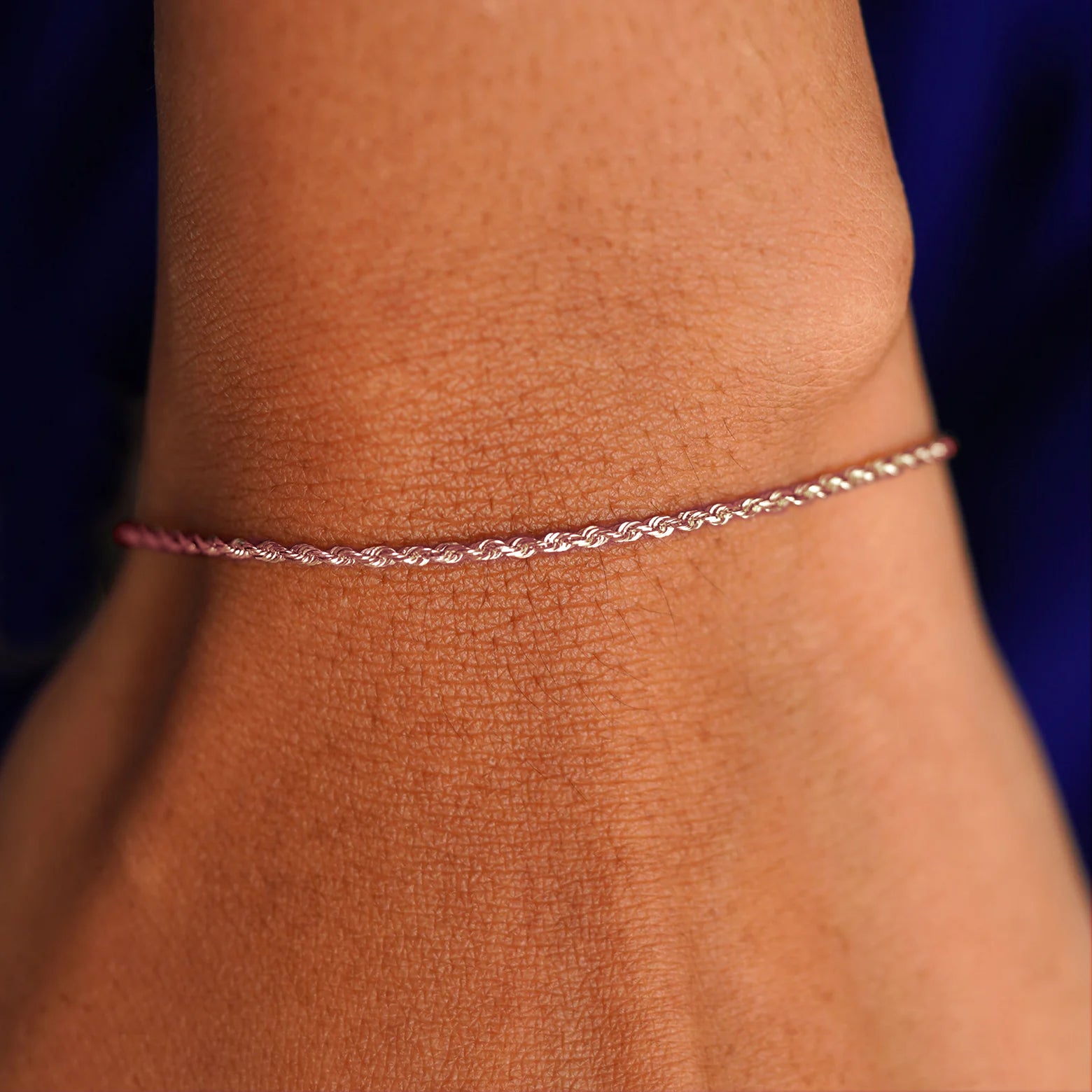 A model's wrist wearing a solid 14k rose gold Rope Bracelet