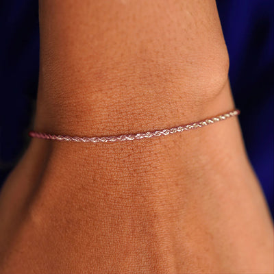 A model's wrist wearing a solid 14k rose gold Rope Bracelet