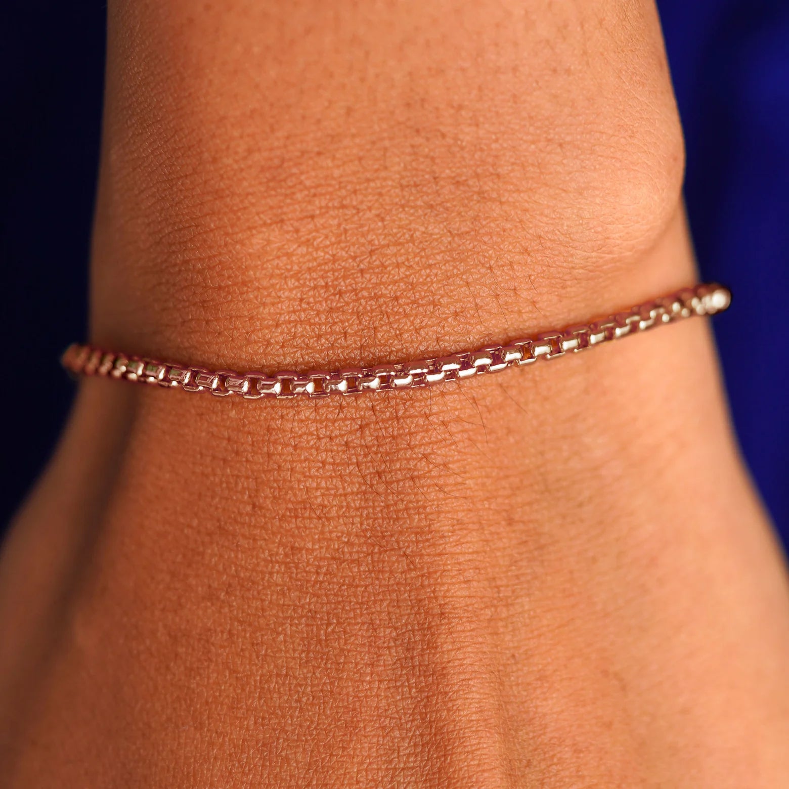A model's wrist wearing a rose gold Round Box Chain Bracelet