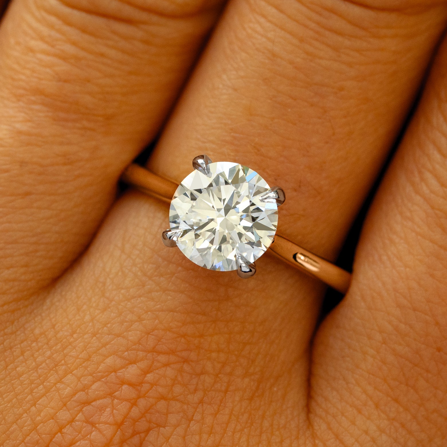 A solid 14k rose gold and platinum Round Lab Diamond Cathedral Set Ring on a model's finger