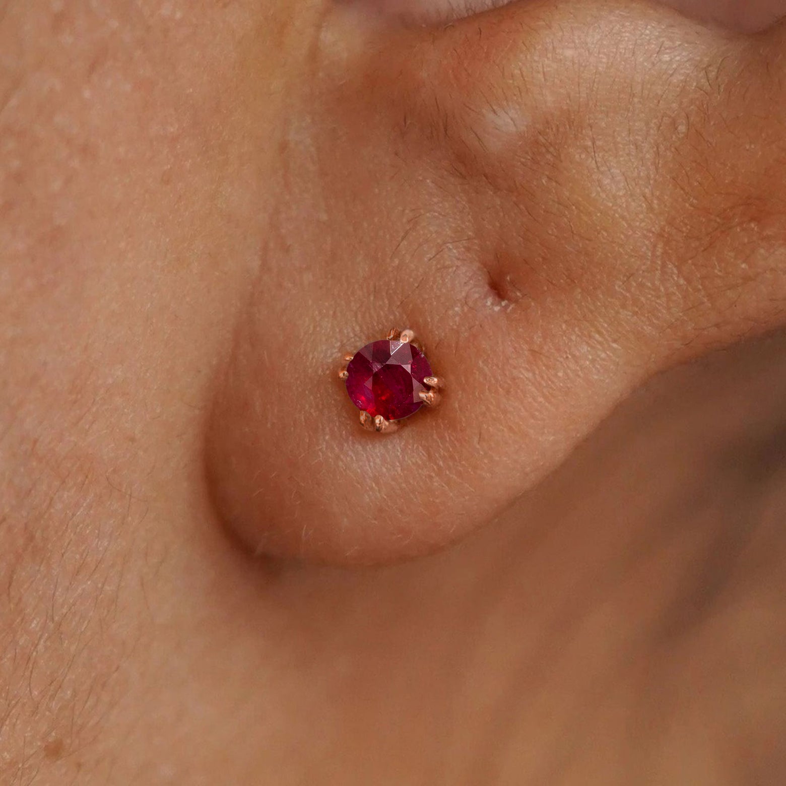 Close up view of a model's ear wearing a 14k rose gold Ruby Earring