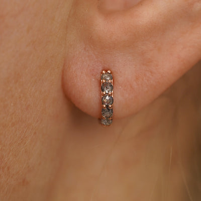 Close up view of a model's ear wearing a rose gold Mini Salt and Pepper Diamond Huggie Hoop