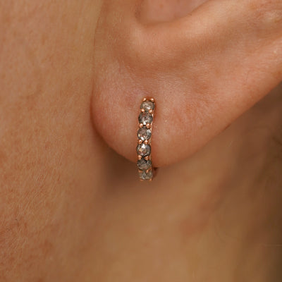 Close up view of a model's ear wearing a rose gold Small Salt and Pepper Diamond Huggie Hoop