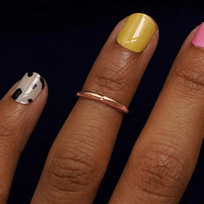 Close up view of a model's hand wearing a rose gold Single Line Toe Ring as a midi ring