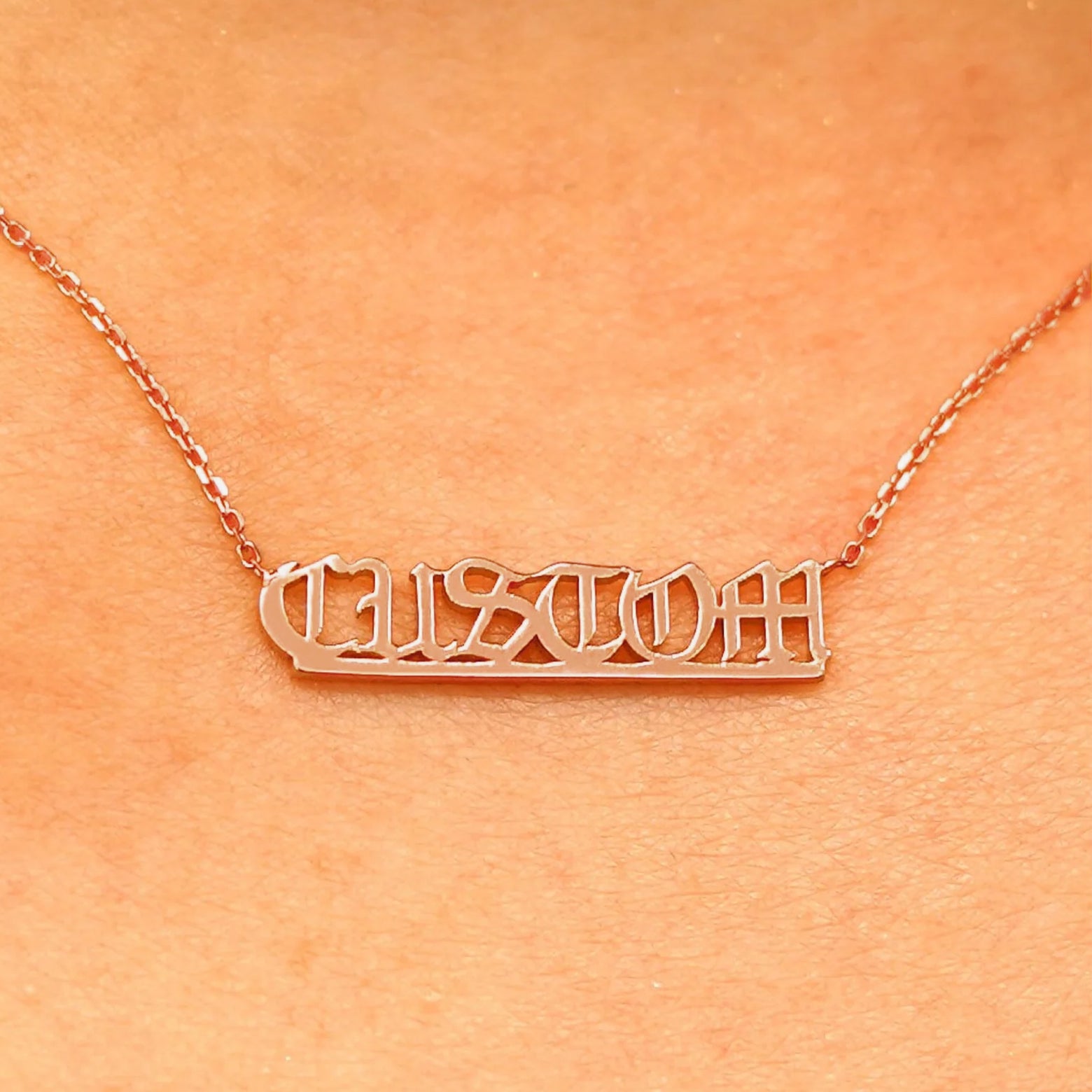 Close up view of a model's neck wearing a Small Custom Nameplate necklace that reads the word Custom