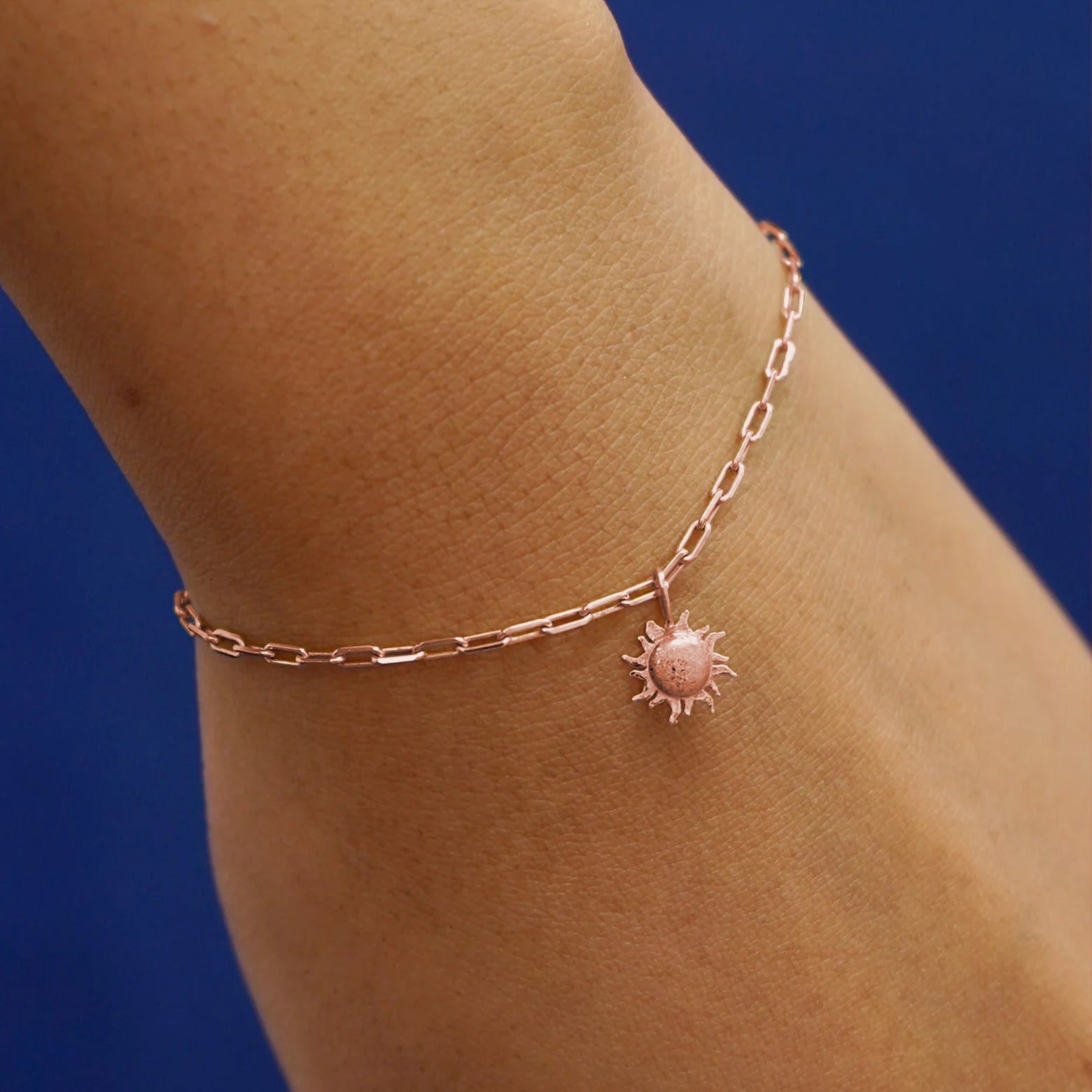 Close up view of a model's wrist wearing a rose gold Sun Charm on a Butch Chain Bracelet