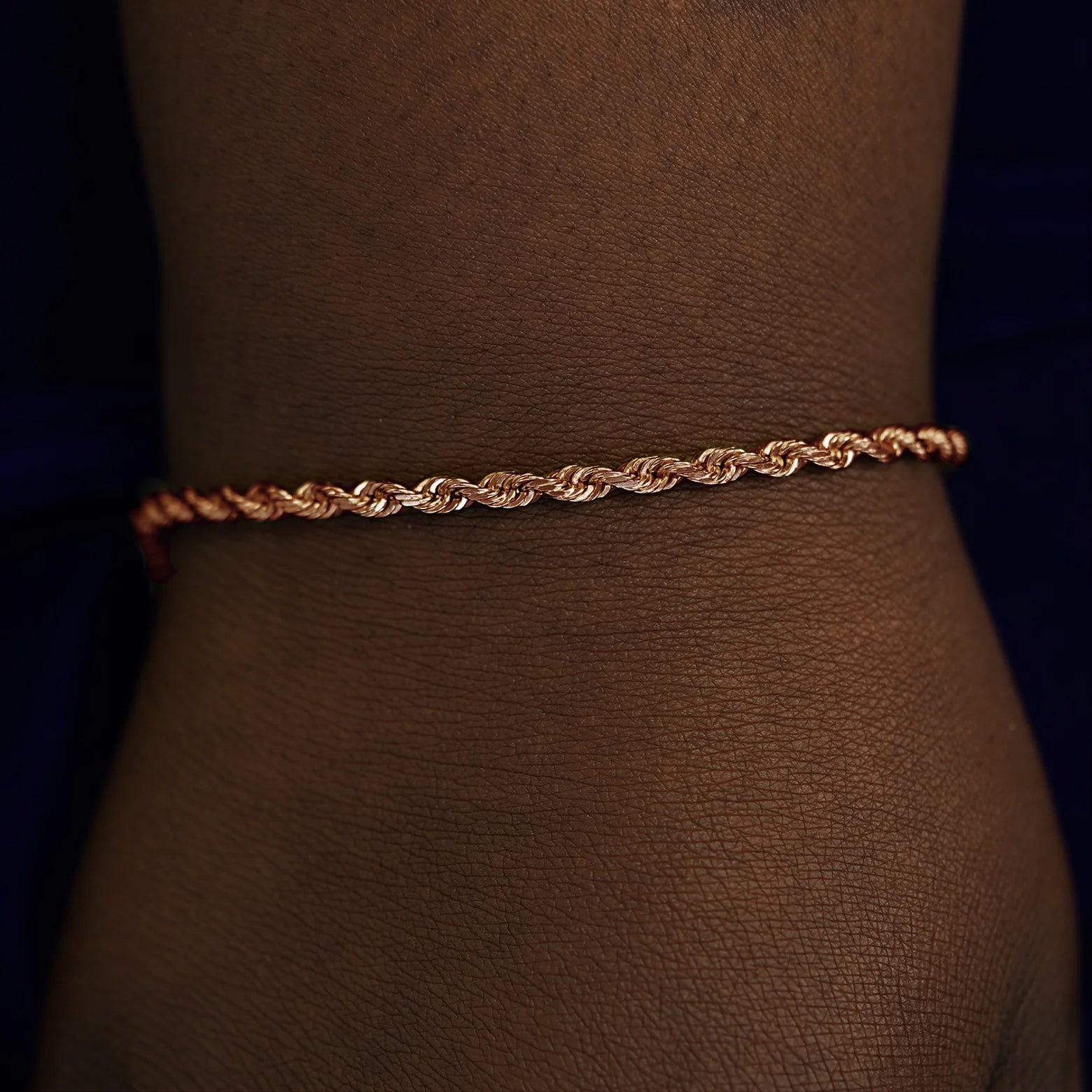A model's wrist wearing a solid rose gold Thick Rope Chain Bracelet