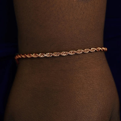 A model's wrist wearing a solid rose gold Thick Rope Chain Bracelet