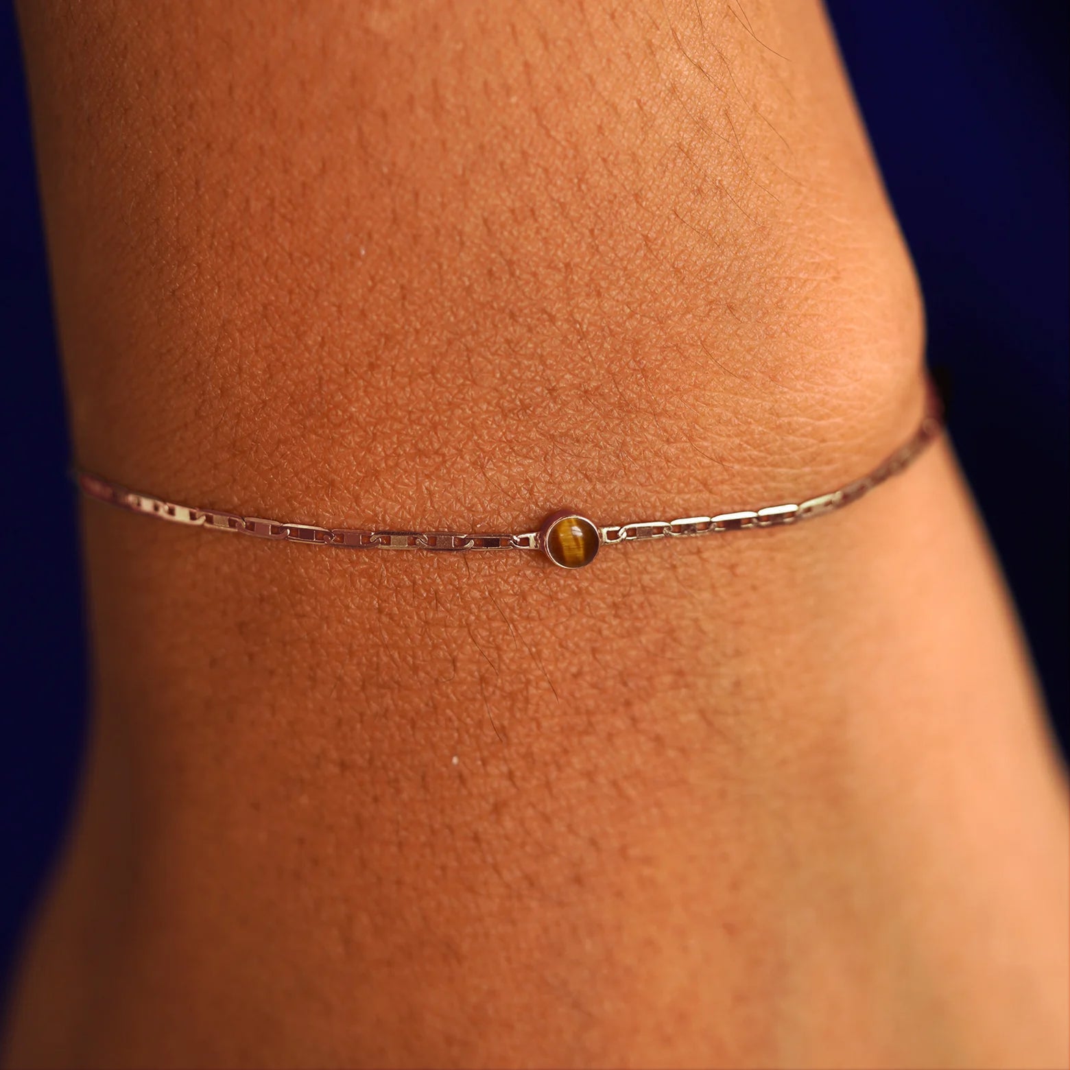 A model's wrist wearing a 14 karat rose gold Tiger Eye Bracelet