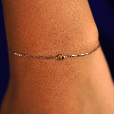 A model's wrist wearing a 14 karat rose gold Tiger Eye Bracelet