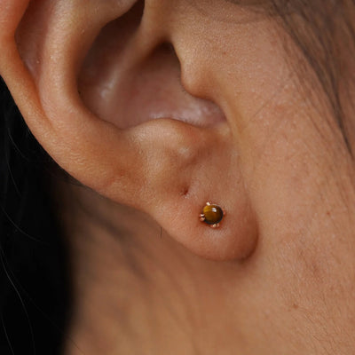 A model's ear wearing a 14k rose solid gold Tiger Eye Earring